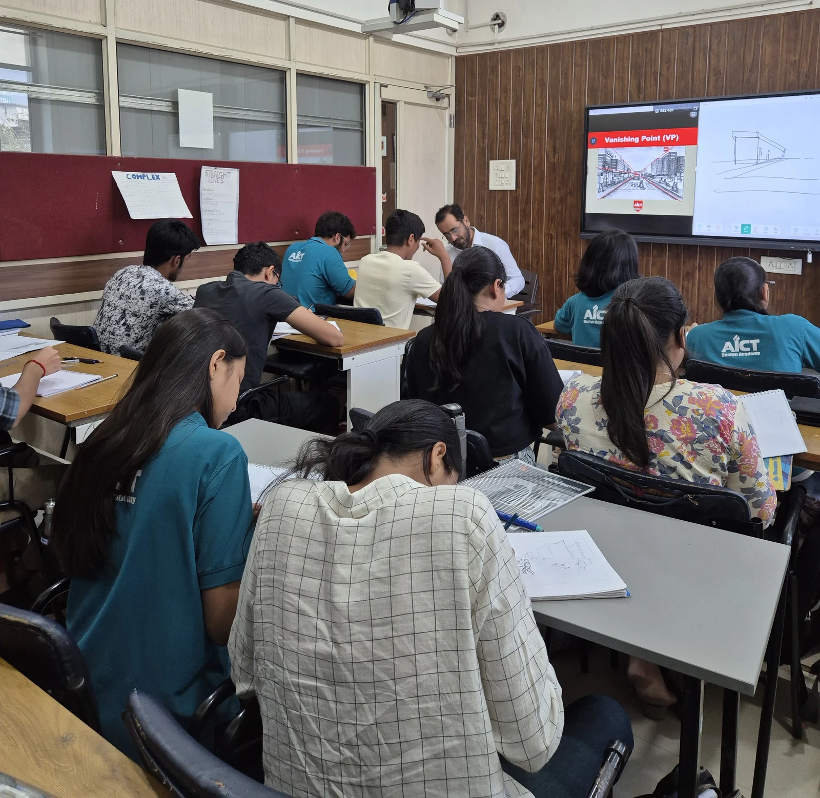 AICT students following a perspective drawing demonstration and practising on paper
