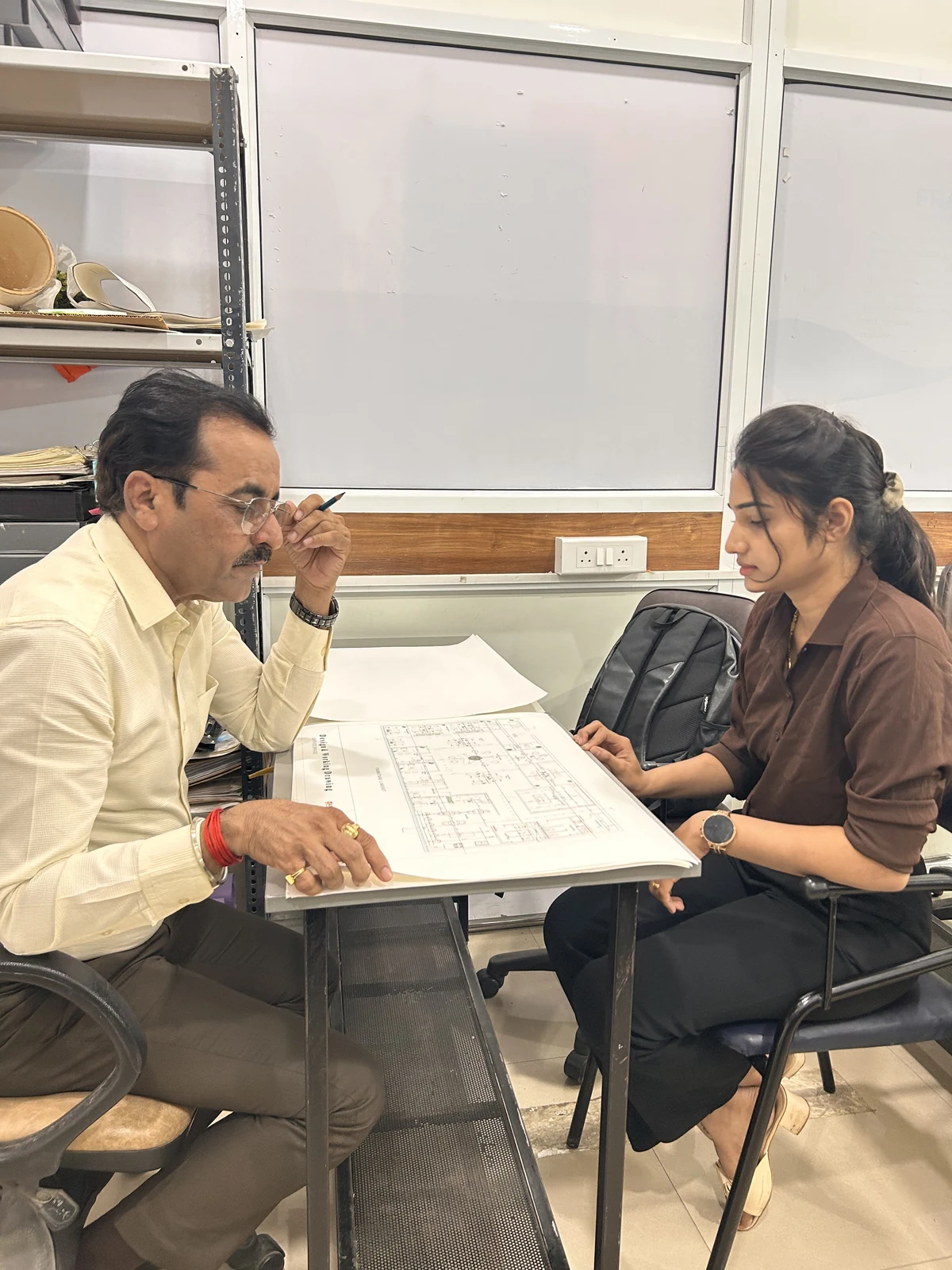 AICT student receiving faculty feedback on a design portfolio and drawings